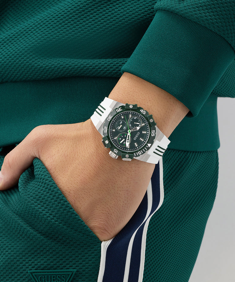 Person wearing a GUESS Mens White Silver Tone Analog Watch with a green and white strap on a green background
