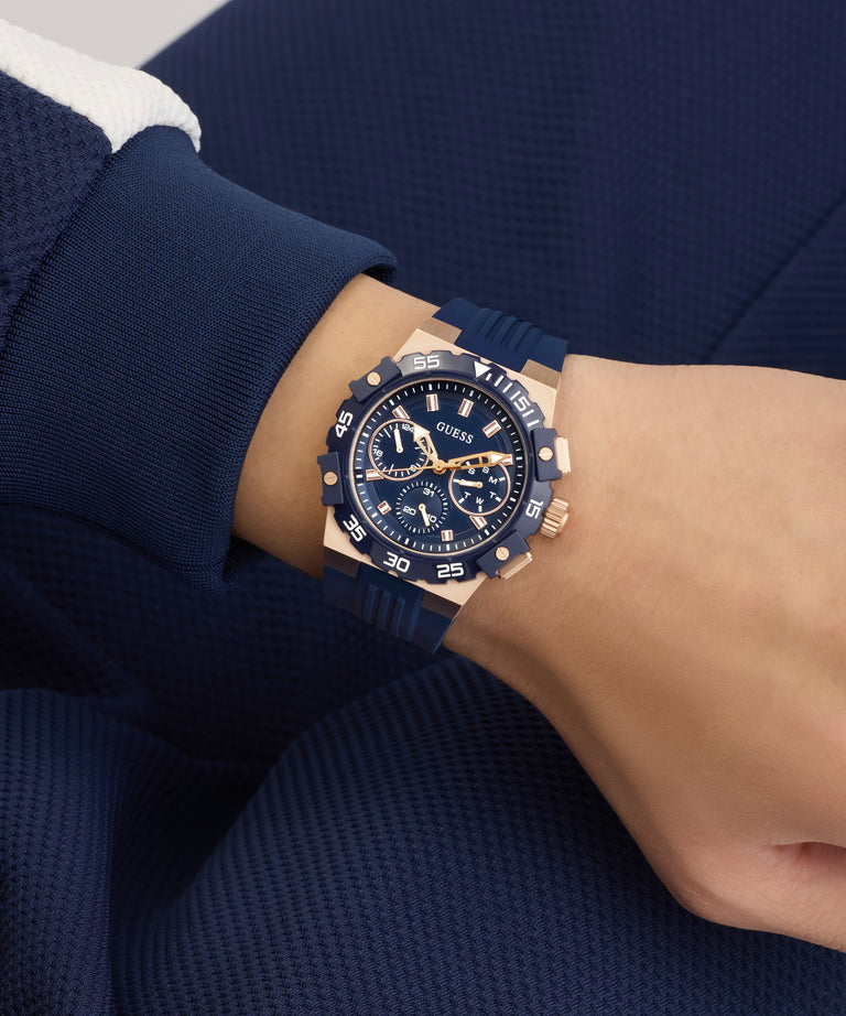 Person wearing a blue and gold GUESS Mens Midnight Blue Rose Gold Tone Analog Watch on a matching blue outfit