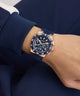 Person wearing a blue and gold GUESS Mens Midnight Blue Rose Gold Tone Analog Watch on a matching blue outfit