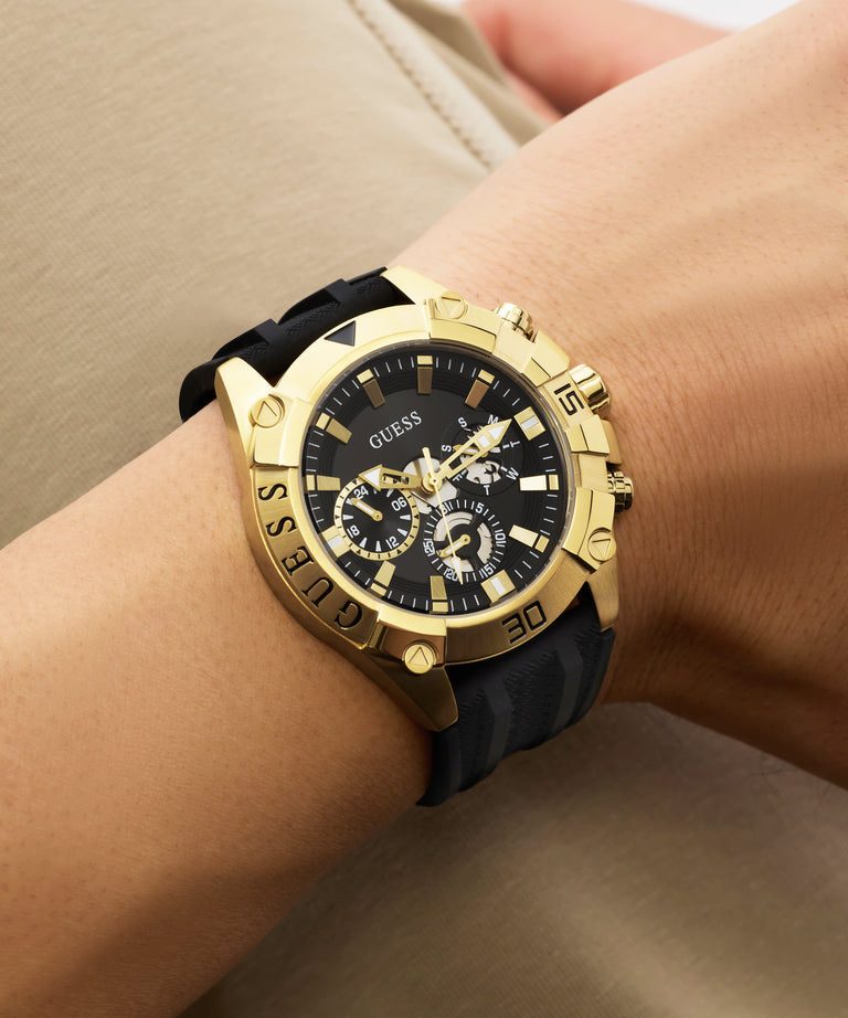 Gold watch with black strap on a wrist against a neutral background