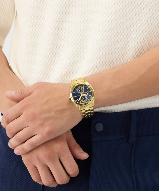 Gold wristwatch on a person's wrist with a neutral background
