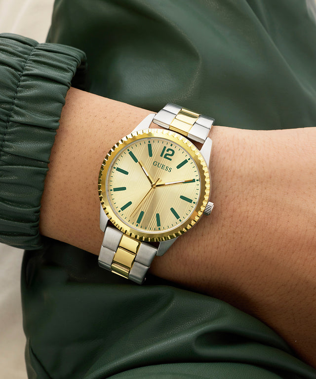 Gold and silver GUESS Mens 2-Tone Analog Watch on a wrist with a green jacket