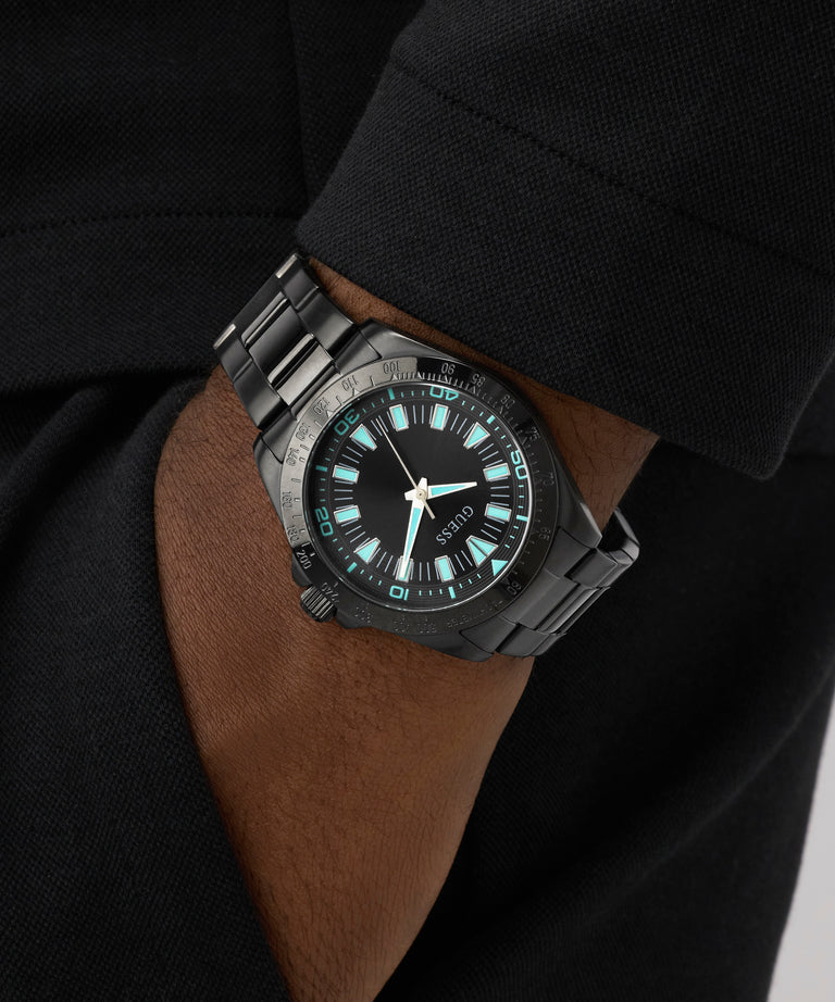 Black wristwatch with blue glowing face on a person's wrist against a dark background