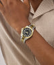 Gold and silver watch on a wrist with a neutral background