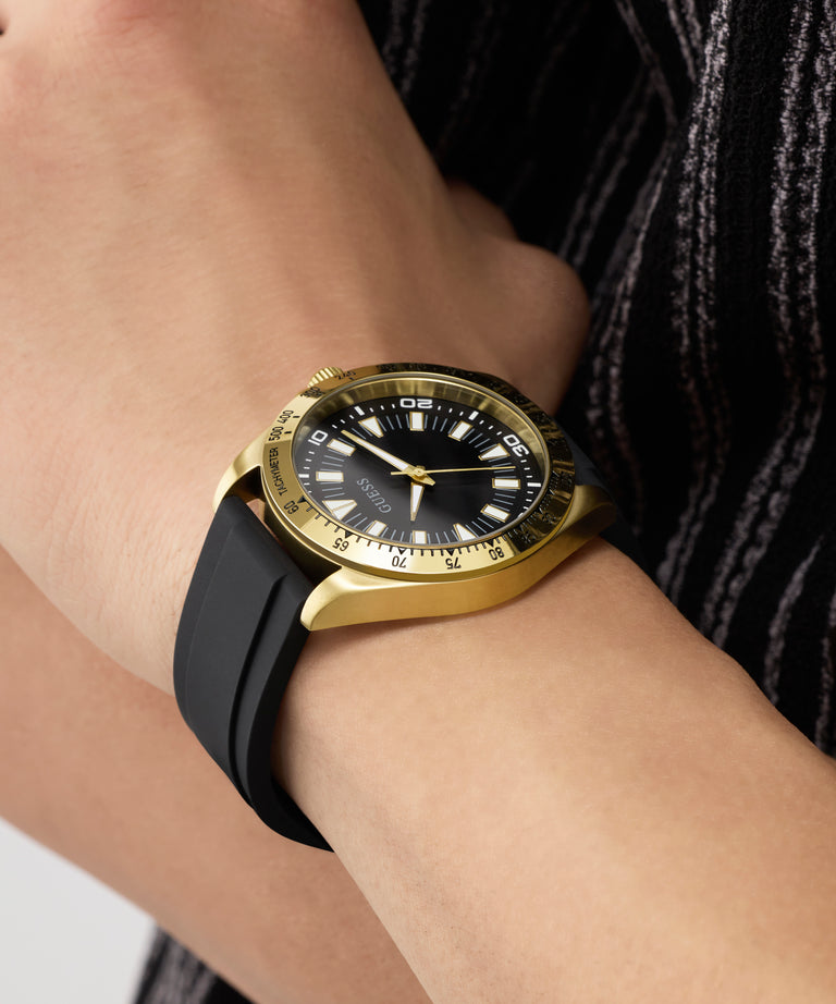 Gold and black watch on a wrist with a blurred background