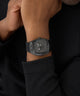 Black GUESS Mens Black Analog Watch on a person's wrist with a dark background