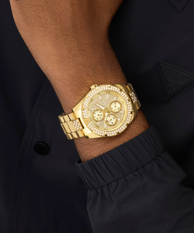 Gold wristwatch with detailed design on a person's wrist against a dark background