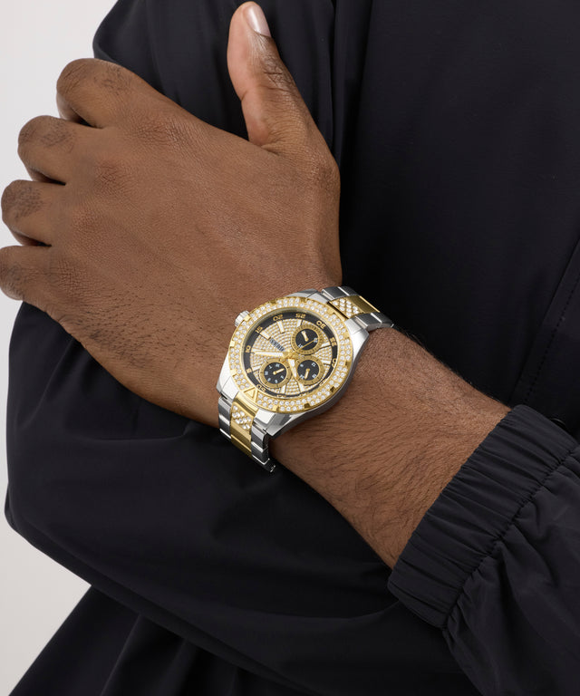 Gold and silver watch on a wrist with a black background