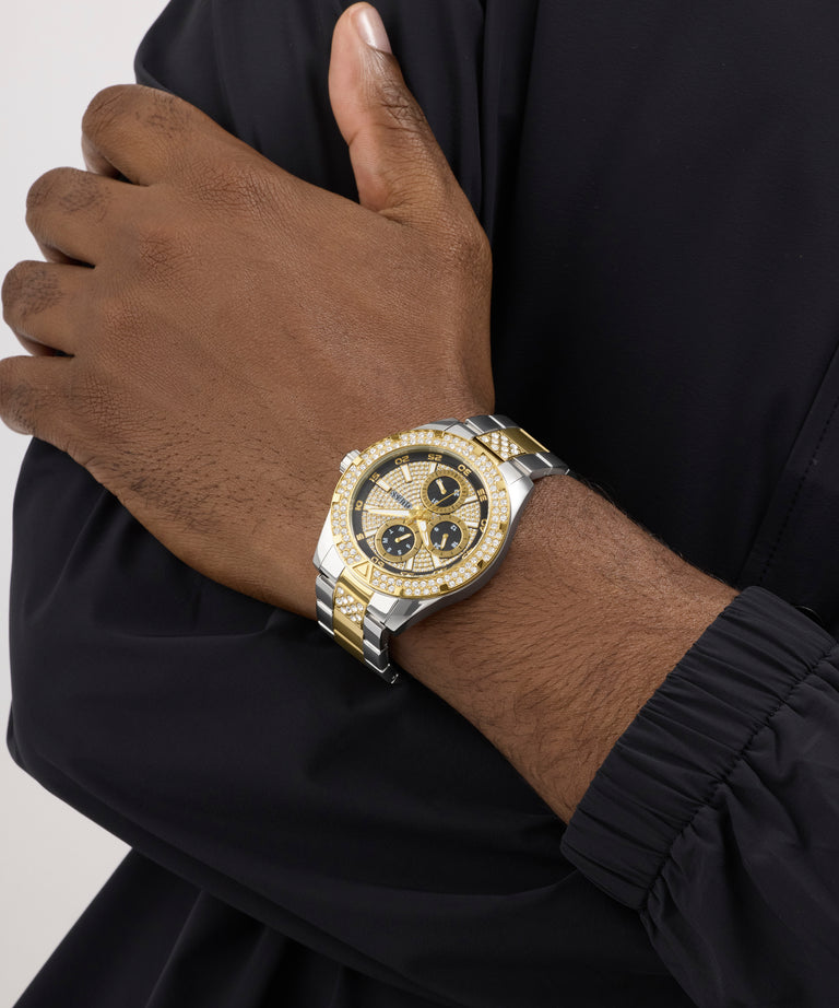 Gold and silver watch on a wrist with a black background