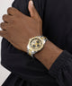Gold and silver watch on a wrist with a black background