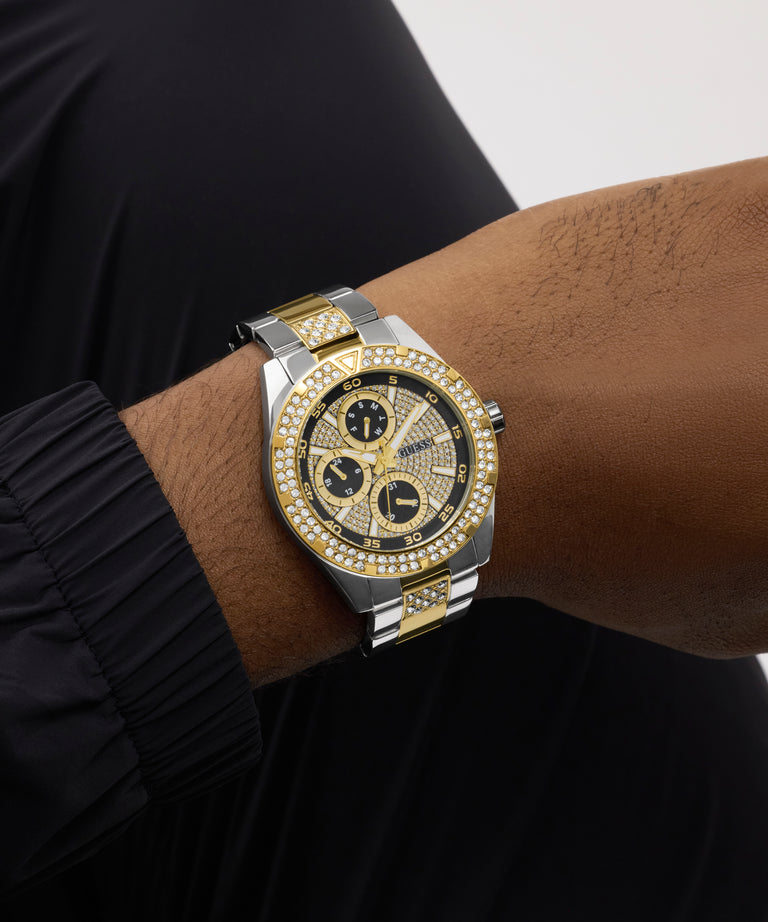GUESS watch with a black and gold face on a wrist against a black background