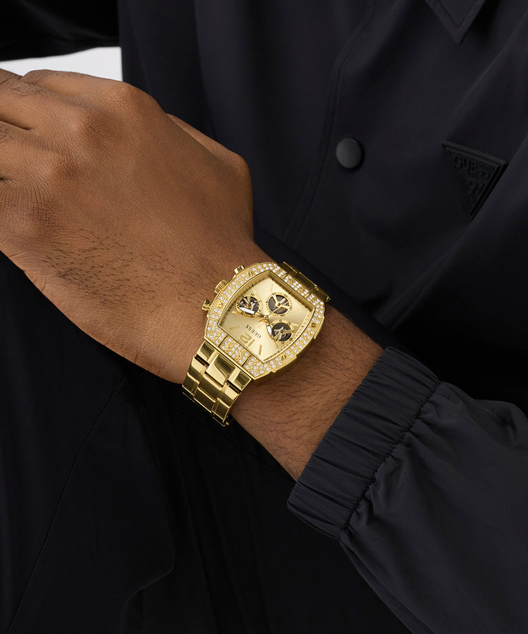 Gold GUESS Mens Gold Tone Analog Watch on a wrist with a black background