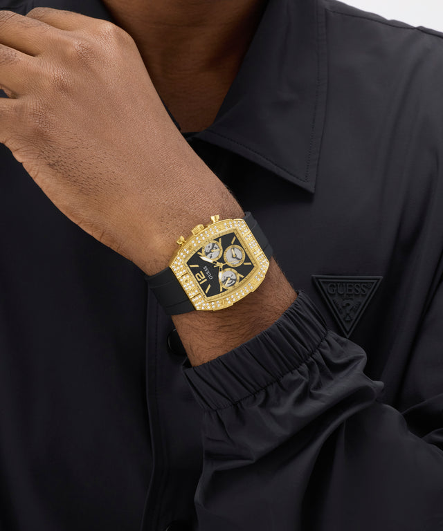 Gold GUESS Mens Black Gold Tone Analog Watch on a person's wrist with a black shirt background