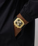 GUESS Mens Black Gold Tone Analog Watch with diamond accents on a person's wrist against a black background