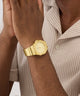 Gold GUESS Mens Jaq Gold Tone Analog Watch on a wrist with a neutral background