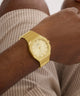 Gold GUESS Mens Jaq Gold Tone Analog Watch on a wrist with a neutral background