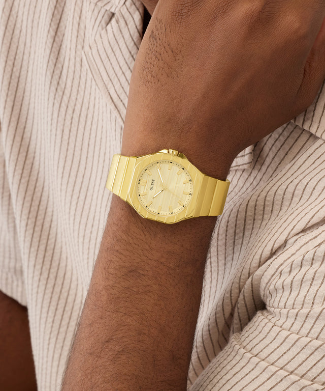 Gold GUESS Mens Jaq Gold Tone Analog Watch on a wrist with a neutral background
