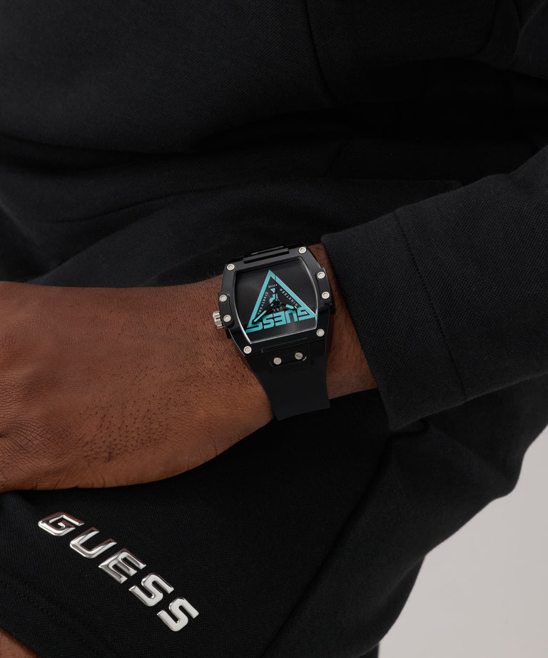Person wearing a black digital watch with a blue screen, sitting on a black surface.