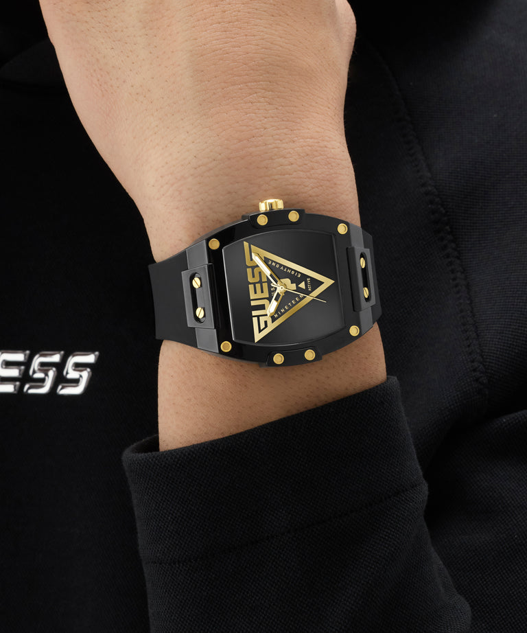 Black and gold GUESS Mens Black Analog Watch on a wrist with a dark background