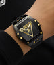Black and gold Guess watch on a wrist with a dark background