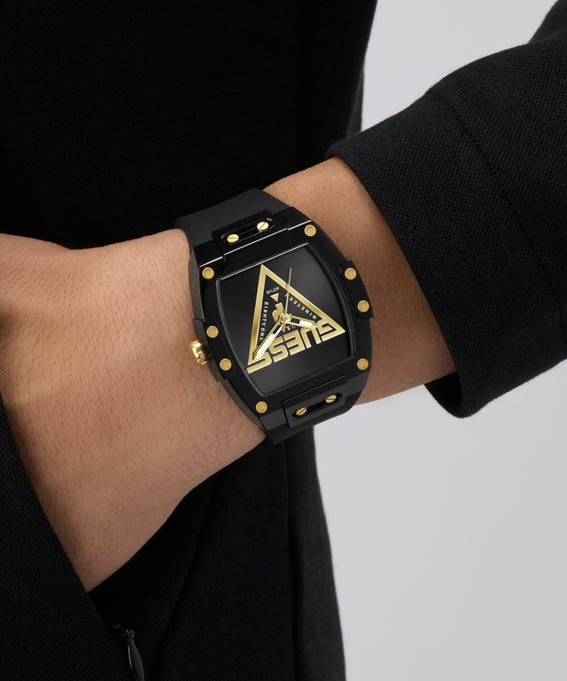 Black GUESS Mens Black Analog Watch with gold accents on a wrist against a neutral background