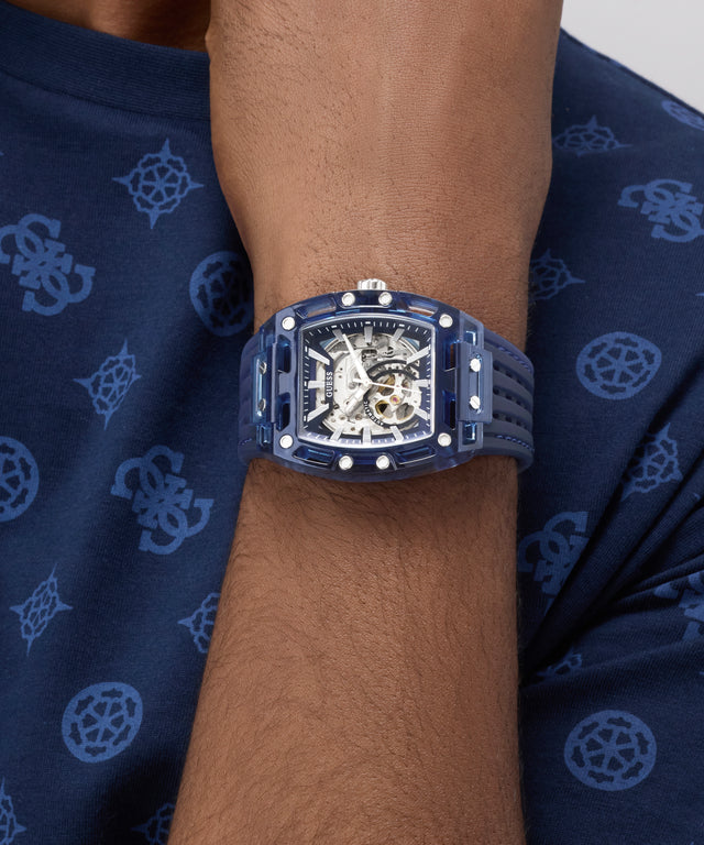 GUESS Mens Blue Analog Watch on a wrist with a dark blue patterned fabric background