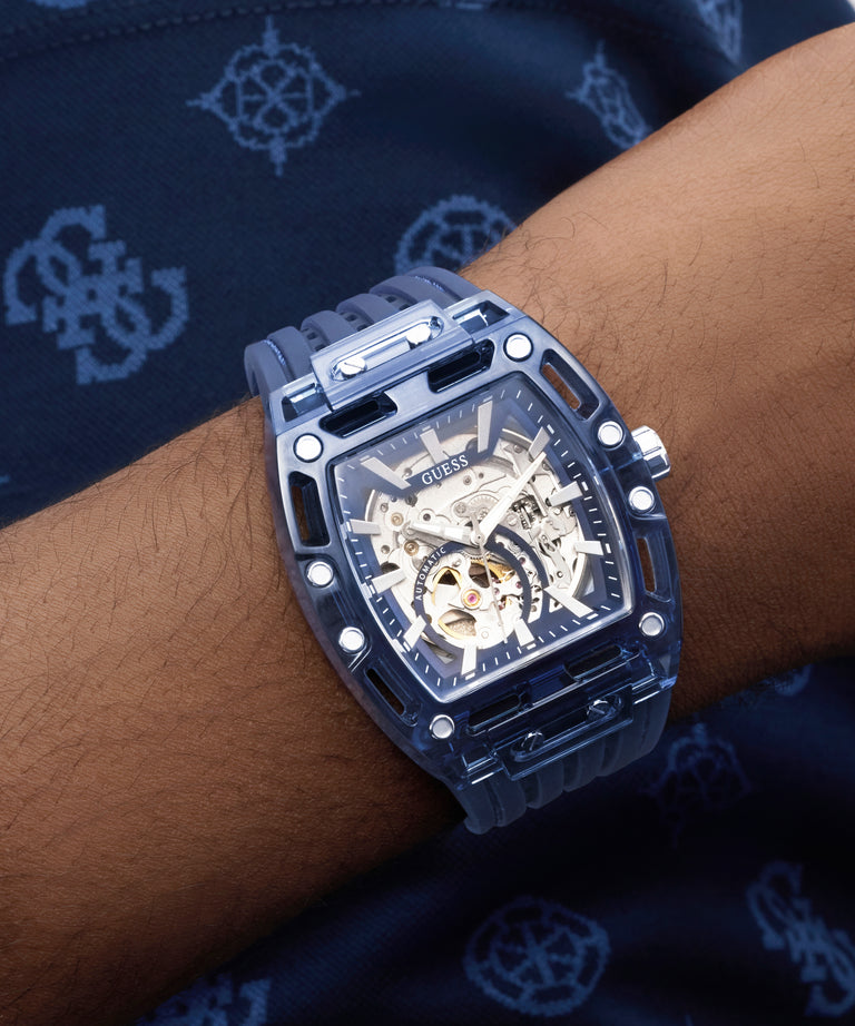 GUESS Mens Blue Analog Watch with transparent case on a wrist against a dark background