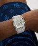GUESS Mens Clear Analog Watch with transparent case on a person's wrist against a blue patterned fabric background