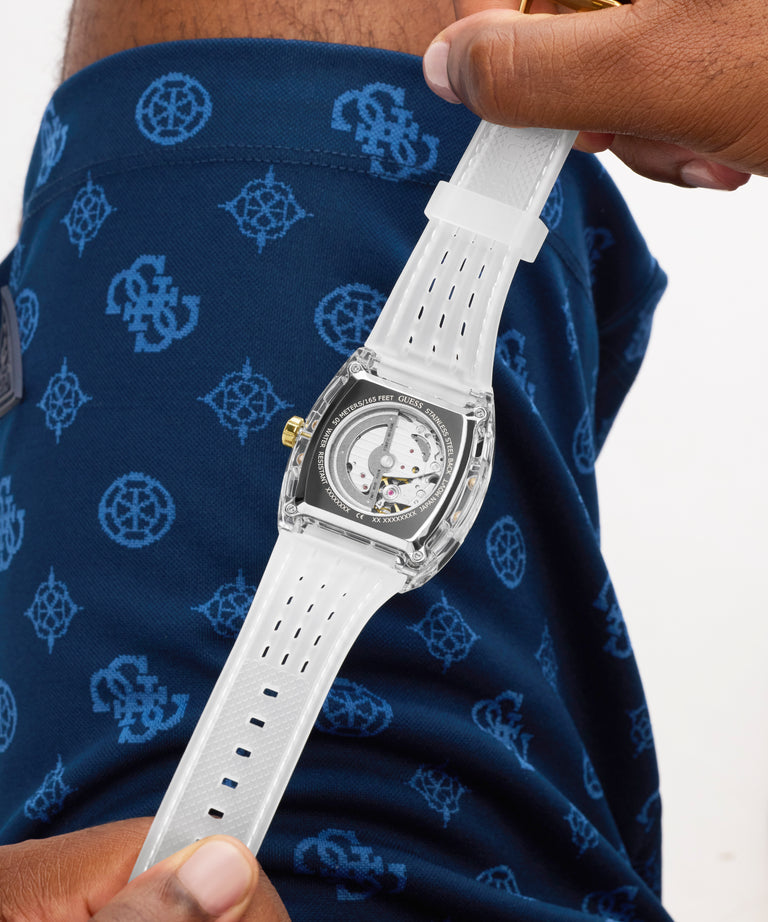 White watch held by a person wearing a navy shirt with blue patterns