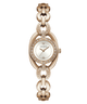 A GUESS women's watch featuring a rose gold-tone oval case with a white dial, crystal-encrusted bezel, and a matching rose gold interlocking link bracelet.