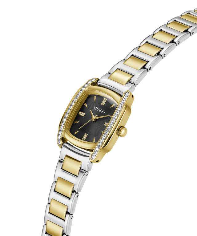 A two-tone yellow gold and silver stainless steel watch by Guess, featuring a green dial, a bezel set with small clear crystals, and a matching two-tone link bracelet, shown on a plain white background. lifestyle