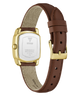 A GUESS women's watch shown from the back, featuring a gold-tone rectangular case, a brown leather strap, and a beige fabric lining.