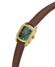 A Guess wristwatch with a gold-tone case, diamond-accented bezel, and a dark green dial, paired with a brown leather strap on a plain white background. lifestyle