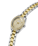 A Guess women's two-tone metal watch with a gold and silver link bracelet, a gold textured dial, and a bezel set with clear crystals, shown on a white background. lifestyle