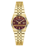 A Guess women's analog watch with a gold-tone metal bracelet, fluted bezel, and a dark burgundy and brown wood-grain dial with gold indices.