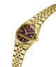 Gold-tone GUESS women's watch with a maroon sunburst dial and a matching gold-tone metal link bracelet, shown on a plain white background. lifestyle