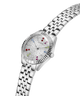 A Guess women's stainless steel watch with a silver-tone metal link bracelet, featuring a white dial embellished with tiny clear stones and colorful crystal hour markers. lifestyle