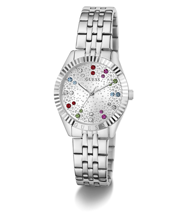 A silver-tone stainless steel wristwatch by Guess with a fluted bezel, a silver-tone link bracelet, and a white dial decorated with tiny floral patterns and colorful crystal hour markers.
