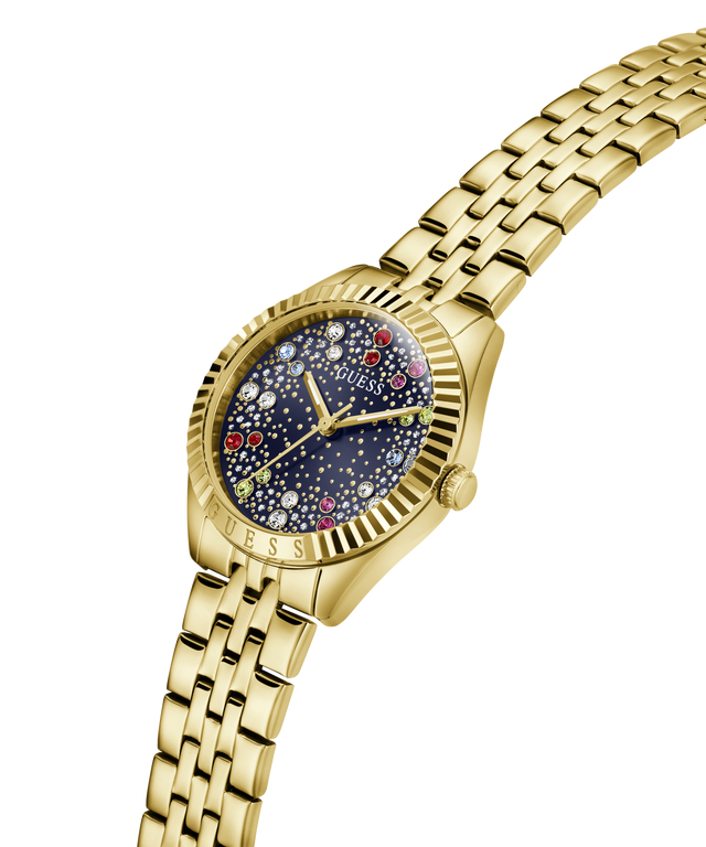 A gold-tone stainless steel wrist watch by Guess, featuring a fluted bezel, a starry navy blue dial with multicolored gem-like accents, and a matching gold-tone link bracelet, shown on a solid white background. lifestyle