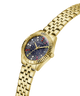 A gold-tone stainless steel wrist watch by Guess, featuring a fluted bezel, a starry navy blue dial with multicolored gem-like accents, and a matching gold-tone link bracelet, shown on a solid white background. lifestyle