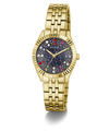 Gold-tone Guess wristwatch with a fluted bezel, gold-tone metal link bracelet, and a dark blue dial decorated with colorful crystal-like star accents.