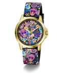 A GUESS women's watch featuring a gold-tone case and a black strap decorated with a colorful Day of the Dead sugar skull and floral pattern, set against a plain white background.
