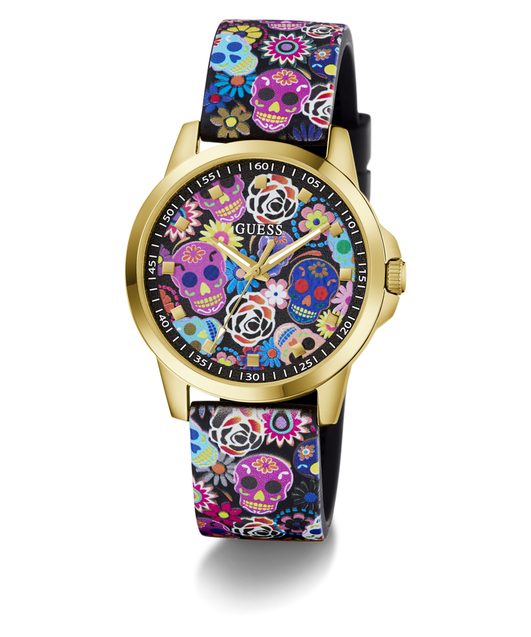 A GUESS women's watch featuring a gold-tone case and a black strap decorated with a colorful Day of the Dead sugar skull and floral pattern, set against a plain white background.