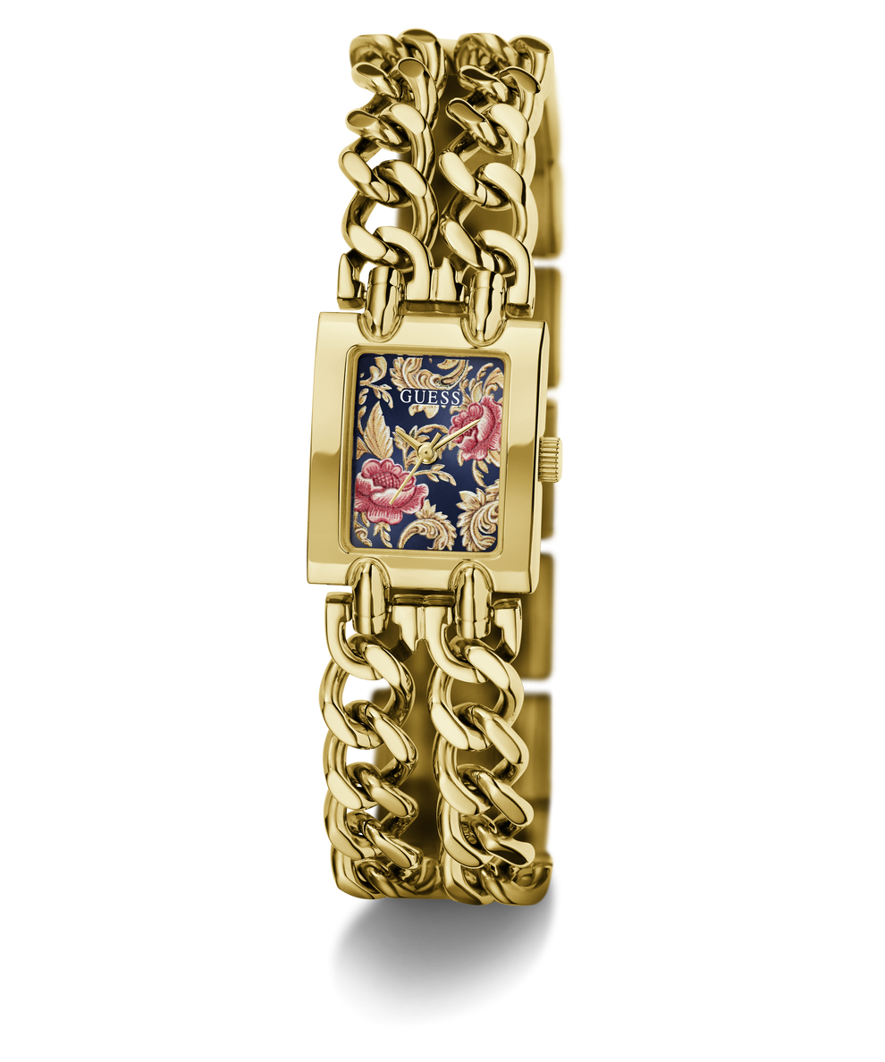 A gold-tone GUESS watch with a thick chain-link bracelet and a rectangular face featuring a navy blue background with pink and gold floral details.