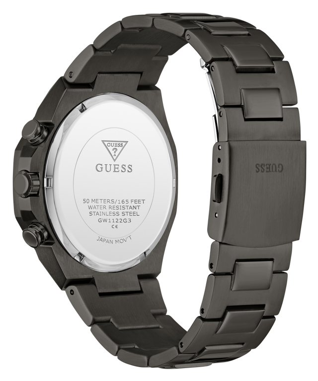 The back view of a GUESS stainless steel watch with a dark gunmetal gray case and integrated metal link bracelet, showing the branded crystal cover.