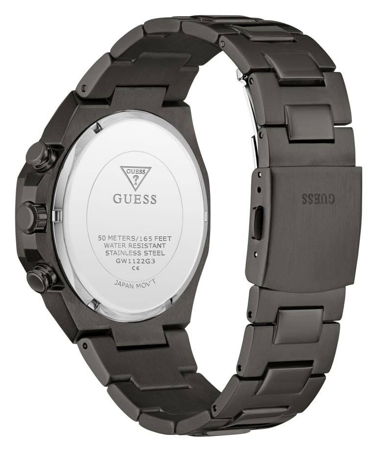 The back view of a GUESS stainless steel watch with a dark gunmetal gray case and integrated metal link bracelet, showing the branded crystal cover.