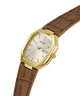 A Guess wristwatch with a gold-tone octagonal case, cream-colored dial, and a brown leather strap, shown on a plain white background. lifestyle
