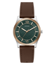 A GUESS men's analog watch featuring a dark green textured dial with gold-tone Roman numerals and hands, a silver-tone case, and a brown leather strap, shown against a plain white background.