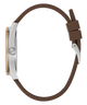 Side profile of a watch with a brown silicone strap, silver-tone case, and a light wood-toned dial on a white background.