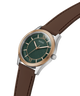 A GUESS men's watch featuring a dark green dial, a rose gold-tone bezel and indices, and a brown leather strap, shown on a clean white background. lifestyle